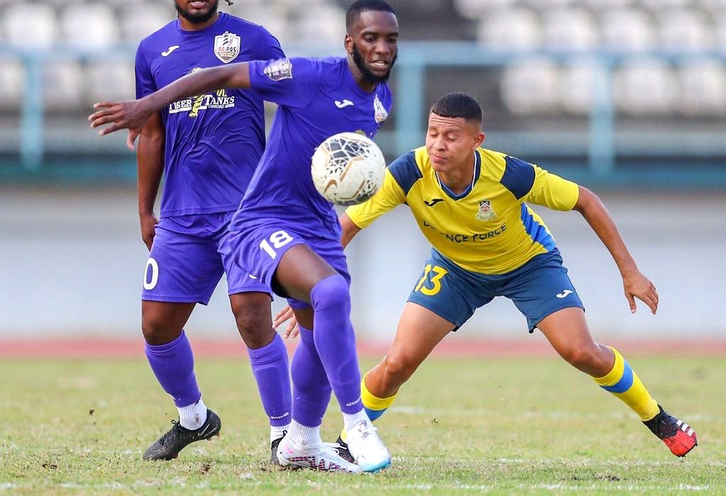 Anthony Charles (No 18) of AC Port of Spain holds off Rivaldo Coryat (No 13) from Defence Force to maintain possession during the T&T Premier League match at the Larry Gomes Stadium in Malabar, Arima, yesterday. AC Port of-Spain won 3-0. ...Daniel Prentice