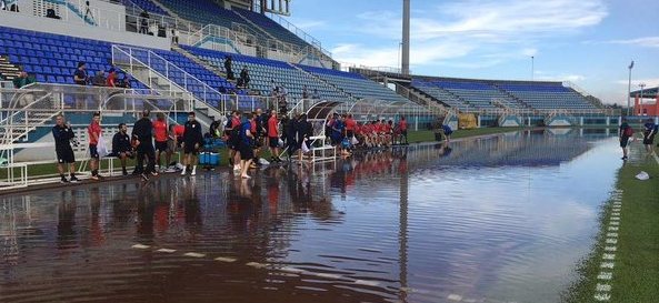 USA team officials and players contemplate whether to walk through the flooded track area to get to the field at the Ato Boldon Stadium in Couva this morning. PHOTO COURTESY US SOCCER