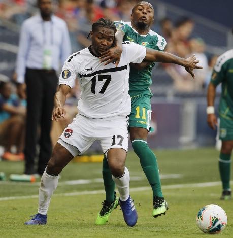 Photo: Trinidad and Tobago defender Mekeil Williams (foreground) is held back by Guyana midfielder Callum Harriott during Gold Cup action on 26 June 2019. (Copyright AP Photo)