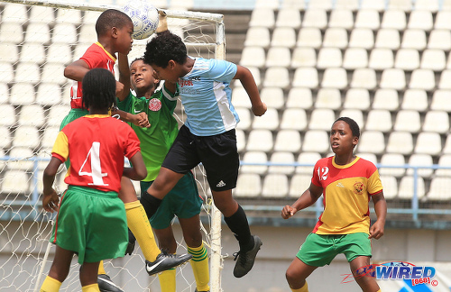 Photo: Trendsetter Hawks goalkeeper Shamael O’Brian (centre) intervenes to thwart QPCC attacker Luca Simon-Thompson (second from right) during RBYL U-11 semifinal action at the Larry Gomes Stadium on 29 June 2019. (Copyright Allan V Crane/CA-images/All Sport)