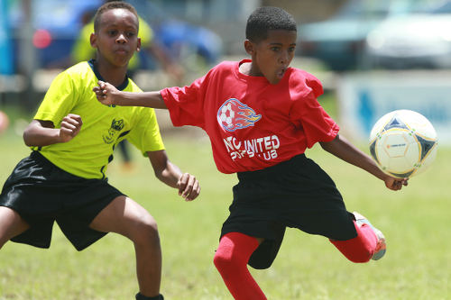 Photo: A Pinto United SC player (right) prepares to strike the ball, despite the attentions of an Adrenaline FA opponent, during Republic Bank National Youth League East Zone Under-12 action on 4 June 2016. Pinto won 4-0. ...(Courtesy Allan V Crane/CAI Sports/All Sport)