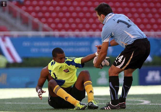 Andre Marchan gets help from a Uruguay player.
