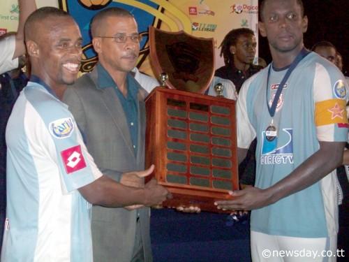 CAREY HARRIS, left, and Errol McFarlane, right, of North East Stars collect the Lucozade Sport Goal Shield Trophy from TT Pro League's CEO Dexter Skeene on Friday night. NE Stars beat San Juan Jabloteh 1-0 in the final. ...Author: JOEL BAILEY