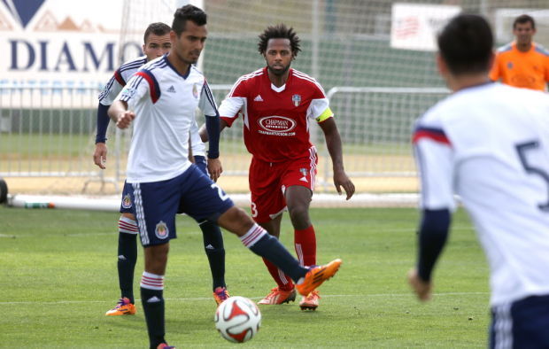 FC Tucson defender Kareem Smith, in red, guards against Chivas USA players in the second half of a Desert Diamond Cup game this week at Kino Sports Complex. Smith used his own frequent flier miles to travel to Tucson from Trinidad.