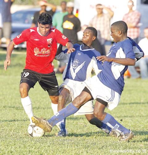 TAKING 'EM ON...is Masee Karamullah, left, attmpting to go past two Malick defenders during yesterday's game. ...Author: AZLAN MOHAMMED (T&T Newsday).