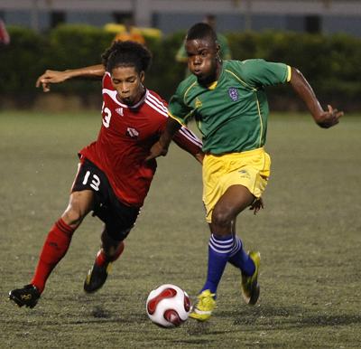 T&T’s Dion Mc Cree attempts to get elude St Vincent and The Grenadines’ Nical Stephens in their Caribbean Football Union Under-20 Group D qualifier at the Marvin Lee Stadium, Macoya on Wednesday night. T&T won 4-1. Photo: Anthony Harris.