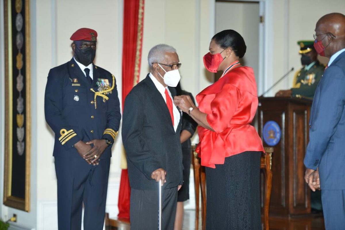Ex-national football coach Edgar Vidale, second from left, receives the Chaconia Medal Silver from President Paula-Mae Weekes as Prime Minister Dr Keith Rowley, right, looks on, at the National Awards 2020, President's House, Port of Spain on Monday, March 7th 2022