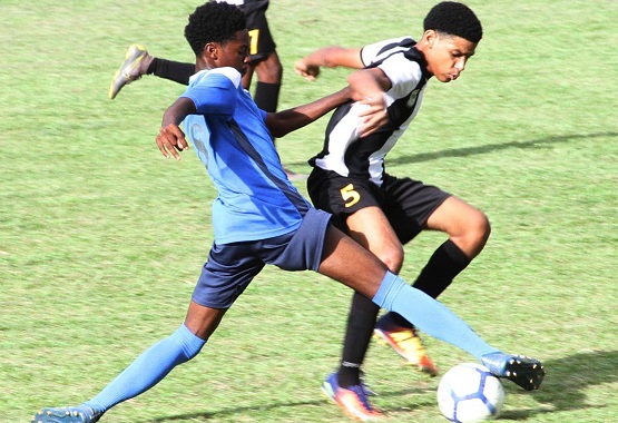 Mikel St. Martin of Holy Cross College(R) wards of a strong tackle for the ball from Dorian Jeffery of Arima North Secondary School,yesterday,during action in the Secondary schools Football League East Zone match at Arima North’s grounds.