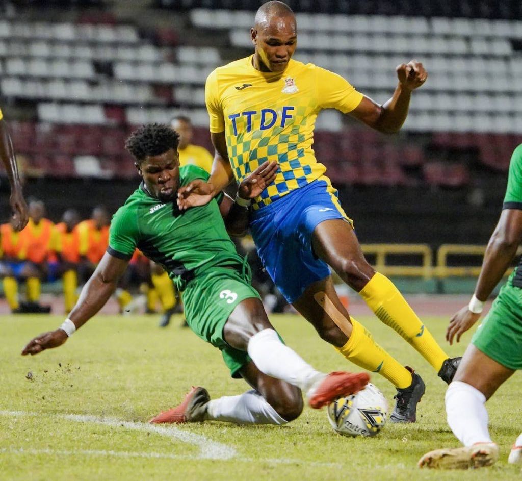Defence Force FC striker Brent Sam (right) gets a heavy skate tackle from W Connection’s Isaiah Garcia (No 3) during the TT Pro League match between Defence Force FC and W Connection FC at the Hasely Crawford Stadium, Port of Spain, on Saturday. - Daniel Prentice/CA-images