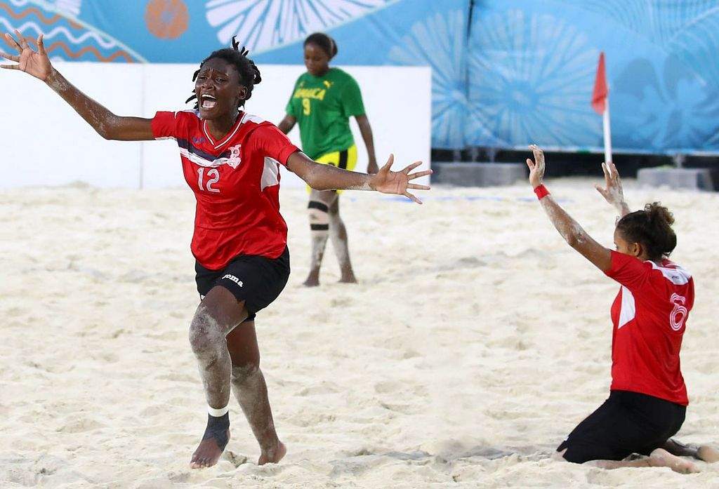 GOLDEN GIRLS: Trinidad and Tobago’s J’Nae Harris, left, races to join her celebrating teammates as another T&T player gives thanks, at the final whistle in the Youth Commonwealth Games Girl’s Beach Soccer gold medal match against Jamaica in Nassau, Bahamas on Saturday. —Photo: AFP