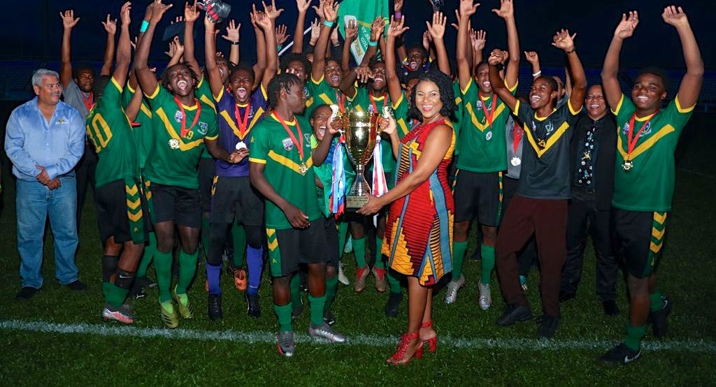 Minister of Education, Nyan Gadsby-Dolly hands over the Tiger Tanks Secondary School Football League Premiership Division trophy to St Benedict’s College’s Tarik Lee while his team celebrates after defeating Fatima College in the final match at the Ato Boldon Stadium in Couva, yesterday. St Benedict's College won 3-1. (Photo by Daniel Prentice)