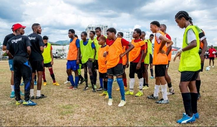 Players chosen from the Trinidad end of the Digicel Kickstart pre-selection clinic listen to instructions from their coaches at the Fatima College ground.