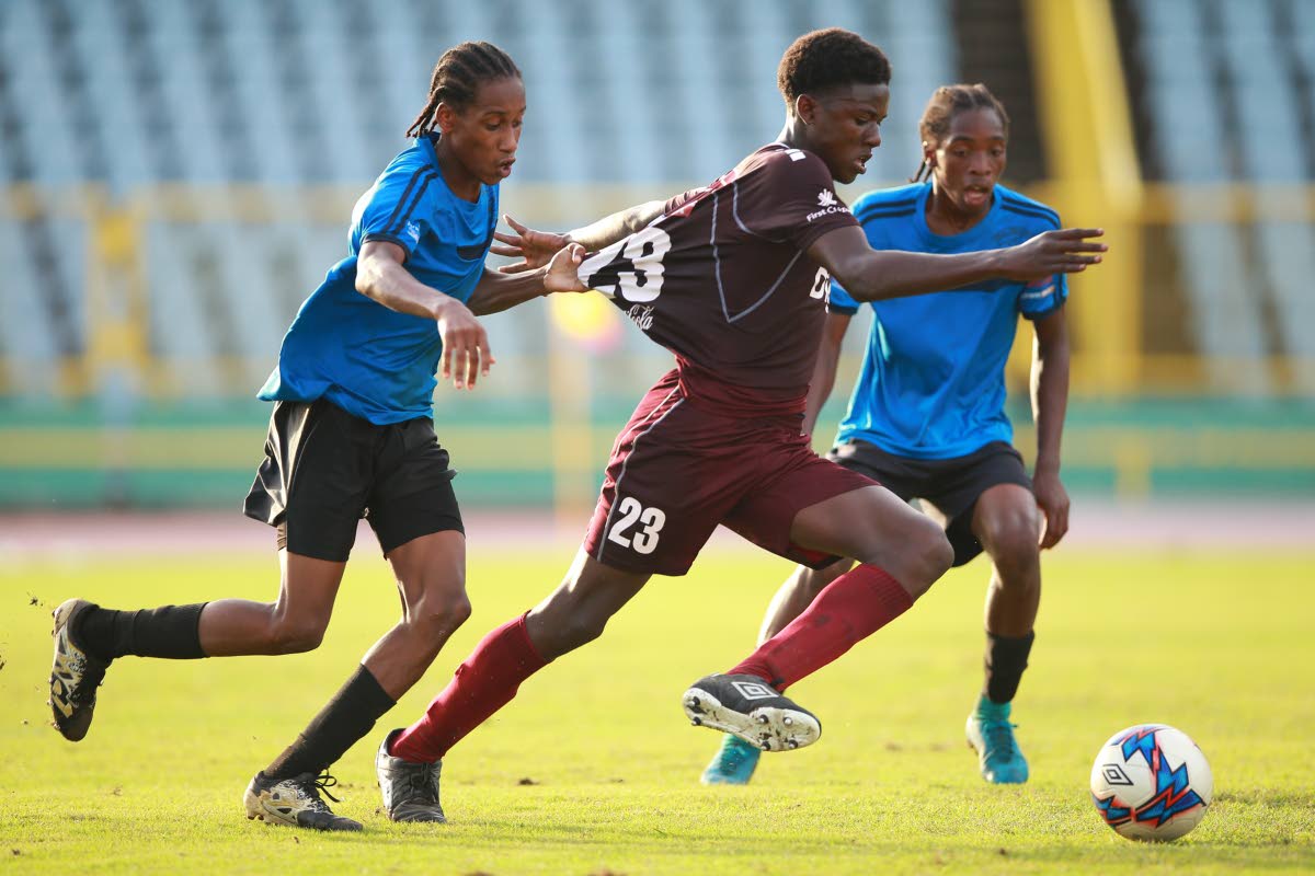 Mucurapo East’s goal scorer Malachi Celestine (#23) has his jersey pulled by Malick’s Zion Carpet during the North Zone quaterfinal between East Mucurapo Secondary and Malick Secondary at the Hasely Crawford Stadium, Mucurapo.