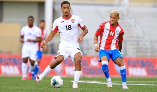 Photo: Trinidad and Tobago midfielder Michel Poon-Angeron (left) passes the ball while Puerto Rico midfielder Devin Vega looks on, during World Cup qualifying action in Mayaguez on 28 March 2021. (via TTFA Media)