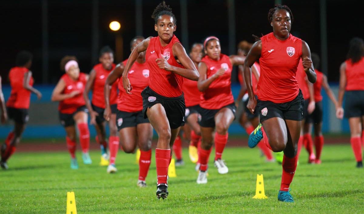 TT’s Under-20 players Brittney Williams (front left) and Natisha John (front right) sprint in a warm-up exercise on Sunday at the Ato Boldon Stadium, Couva.