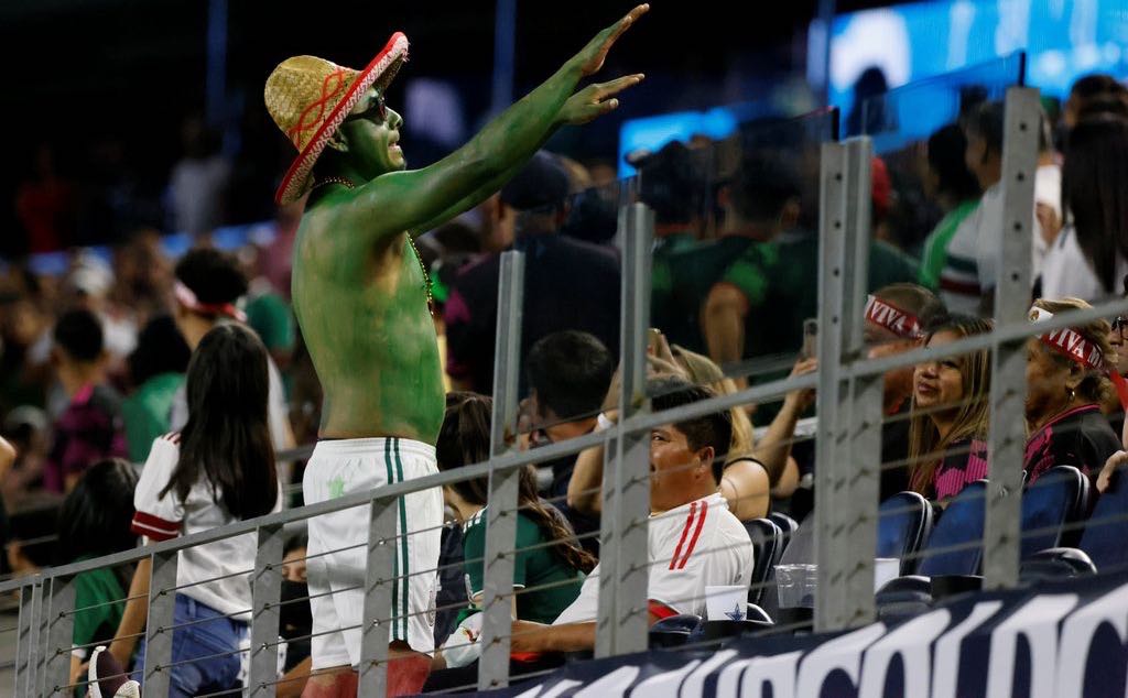 A Mexico fan tries to calm down the crowd, which was threatened with a suspended game as Mexico played to a 0-0 draw against Trinidad and Tobago, during the second half of a CONCACAF Gold Cup Group A soccer match in Arlington, Texas,USA on Saturday. (AP Photo/Michael Ainsworth)  Michael Ainsworth