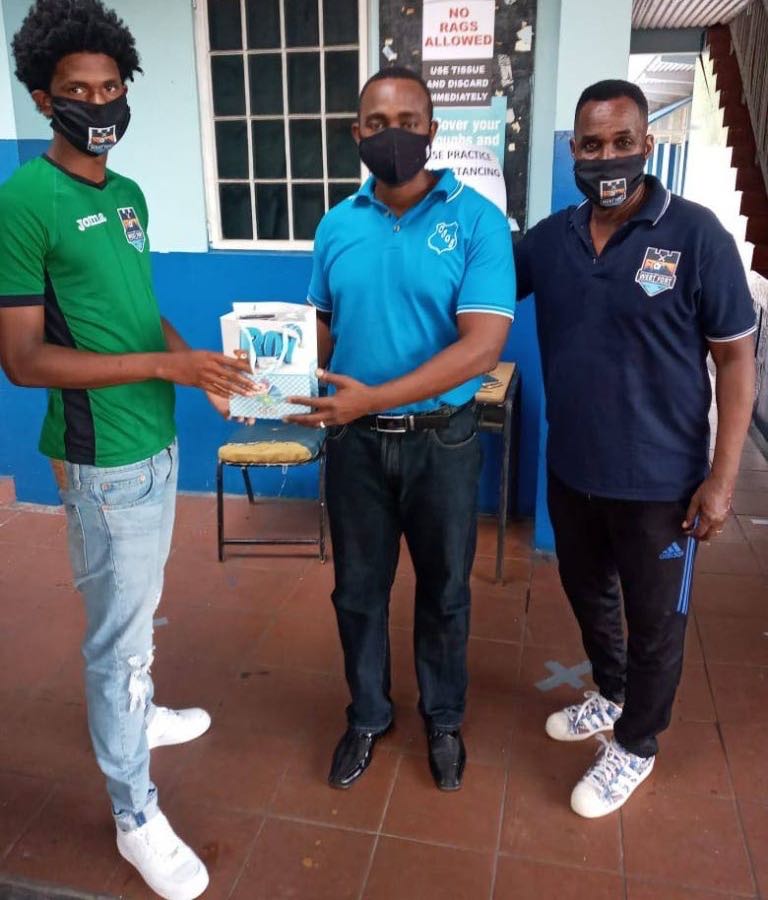 Real West Fort United and national pool player Jahiem Mc Fee, left, presents a Crystal Stream Government Primary School teacher with protective masks for SEA students. At right is club technical director Ron La Forest - 