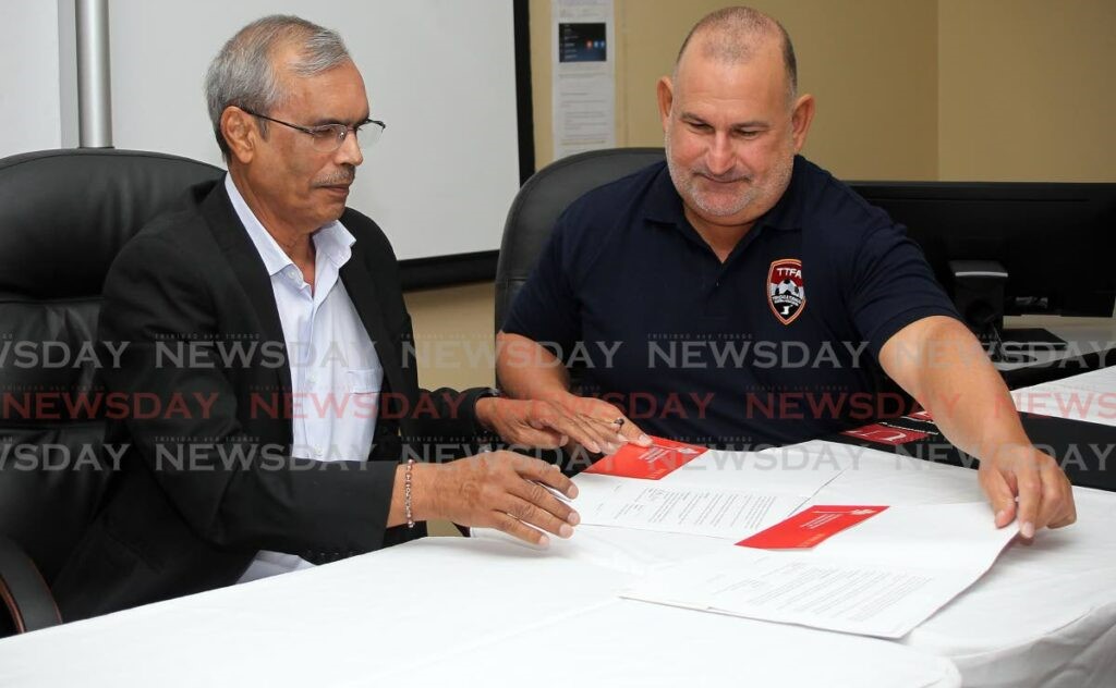 University of Trinidad and Tobago president Prakash Persad, left, signs an MOU with Robert Hadad, chairman of the FIFA-installed TT Football Association normalisation committee at UTT Chaguanas campus on Tuesday. - Photo by Lincoln Holder