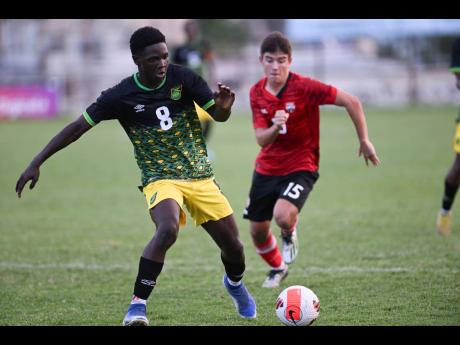 Jamaica’s Ronaldo Barrett moves away from Trinidad and Tobago’s Michael Chaves during their Under-17 friendly international at the Anthony Spaulding Sports Complex yesterday.