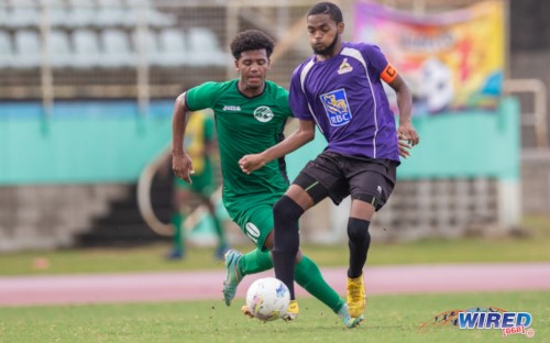 World Class Soccer defender Keshawn Diaz (right) passes the ball under pressure from W Connection forward Caleb Boyce during their NLCL U19 Community Cup semifinal clash at the Mannie Ramjohn Stadium on 19 February 2023. (Copyright Daniel Prentice/ Wired868)