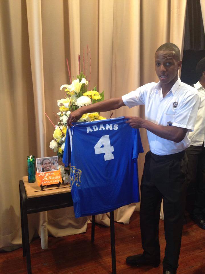 Yohance Alexander, holds up an authentic replica of a jersey that was given to the family of Akeem Adams.