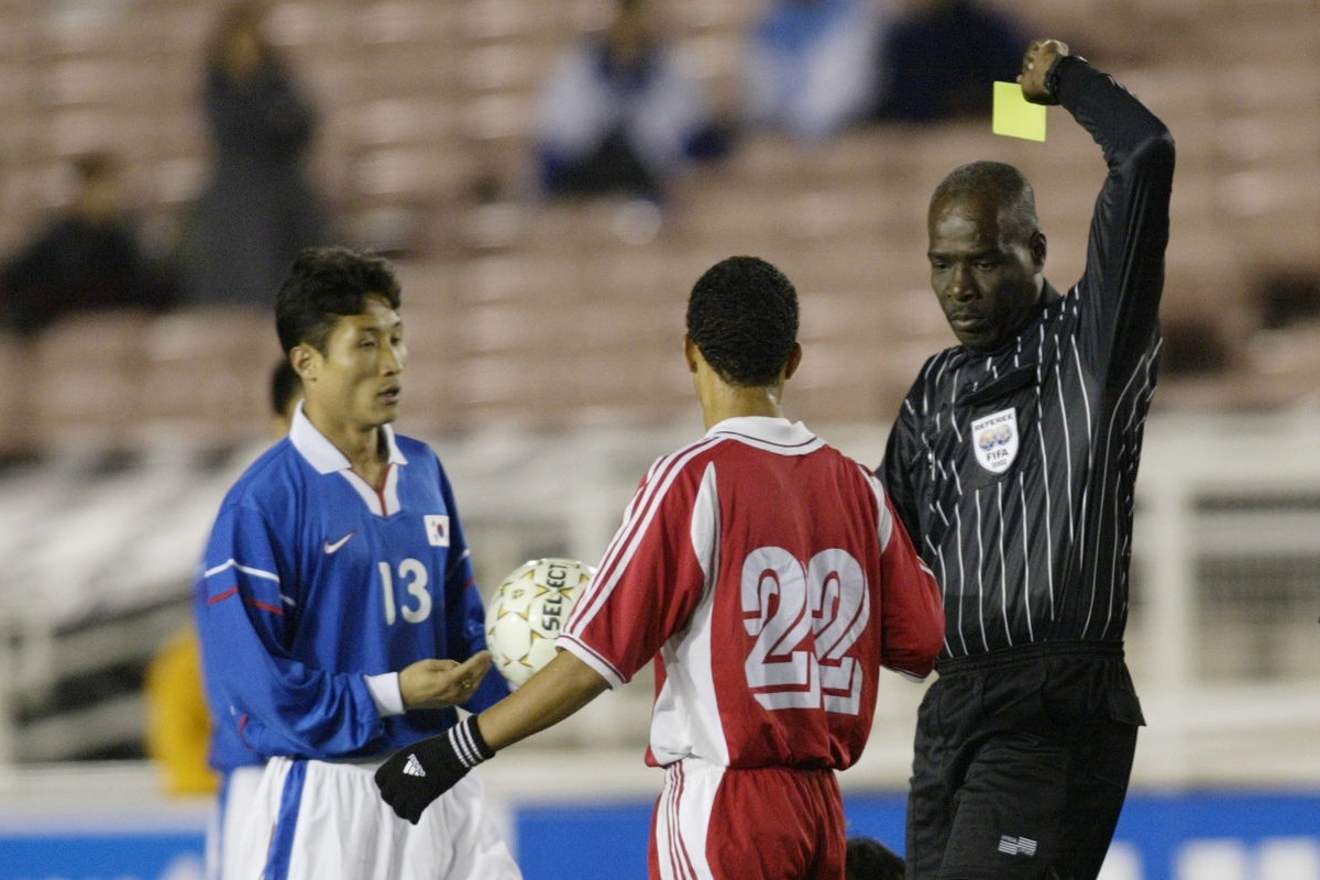 23 Jan 2002: Referee Noel Bynoe gives a yellow card to Rene Estraqda #22 of Cuba in their first round CONCACAF Gold Cup match at the Rose Bowl in Pasadena, California. The final score was South Korea 0-Cuba 0, with South Korea advancing due to goal differential. DIGITAL IMAGE. Mandatory Credit: Stephen Dunn/Getty Images