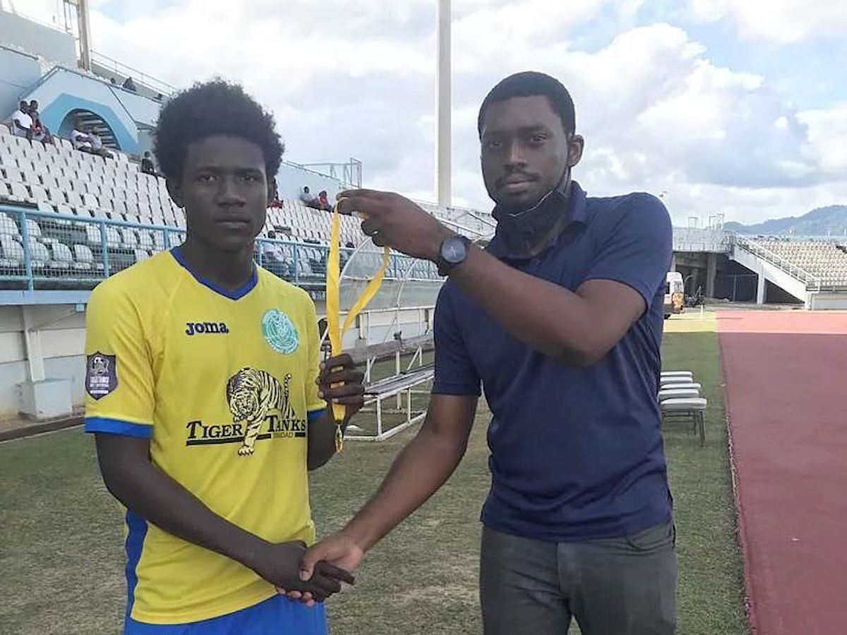 Trendsetter Hawks' Malachi Celestine (left) being presented with the Man of the Match award by Match Commissioner Brandon Greene (right) for his performance during a 4-2 win against Caledonia AIA on April 24th 2022.