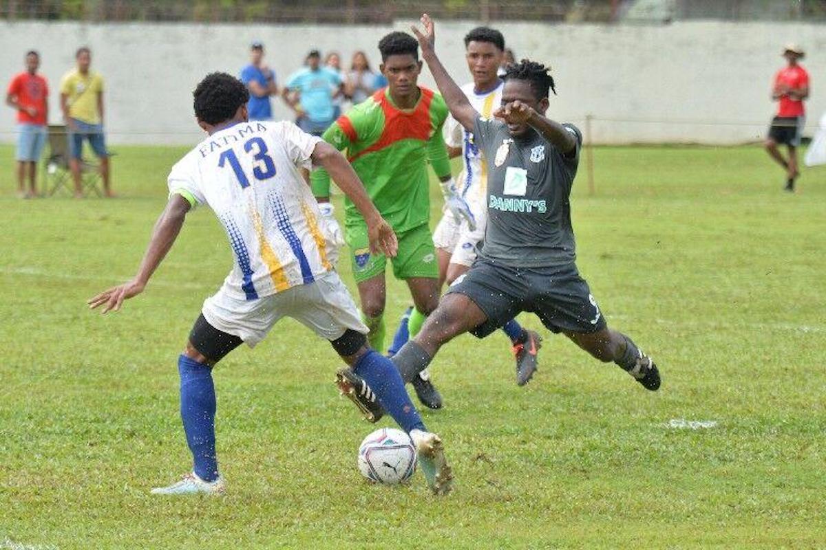 Nathaniel O’Garro of Naparima College, right, makes a nuisance of himself and forces the ball off Fatima College captain Christian Bailey to give ‘Naps’ the lead in this Secondary Schools Football League Premier Division match at Fatima Ground, yesterday September 17th 2022. Bailey was credited with the own goal, but his side rallied for a 2-1 win. —Photo: ROBERT TAYLOR