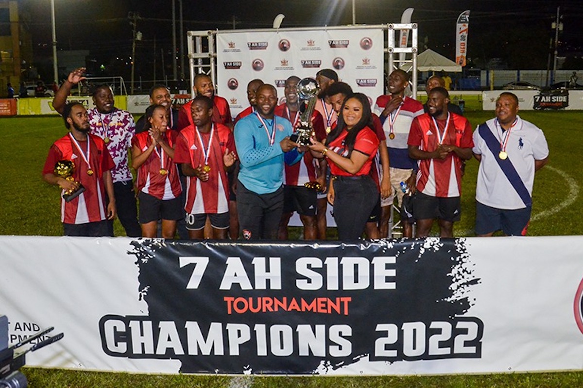 THRILL OF VICTORY: Sport and Community Development Minister Shamfa Cudjoe lifts the trophy along with Kevin Graham, goalkeeper of the triumphant Organ Youths, while the rest of the team celebrate their victory in the inaugural 7-Ah-Side Football Tournament, at the Hasely Crawford training ground in Port of Spain, on Sunday. Photo: KL Photography