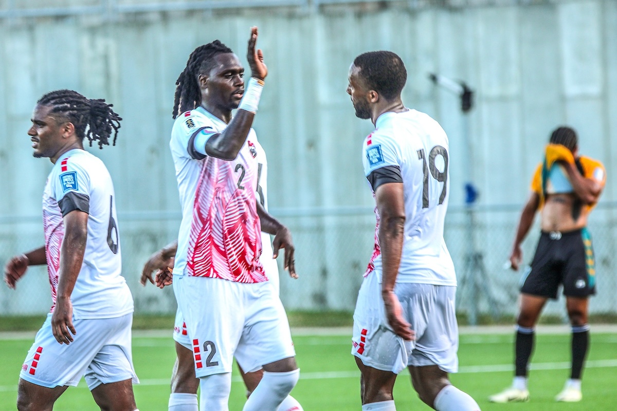 Trinidad and Tobago captain Aubrey David, centre, congratulates striker Malcolm Shaw, right, on his goal while Duance Muckette, left, joins in the celebration during their 7-1 win over Bahamas in their second match in Group B of the Second Round of FIFA CONCACAF World Cup Qualifiers at the St Kitts and Nevis Football Association Technical Centre, Basseterre on Saturday, June 8th 2024.