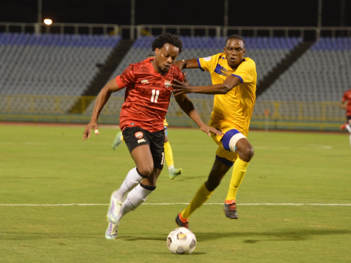 RACE ON: Trinidad and Tobago’s Levi Garcia, left, tries to elude Barbados’ Mario Williams during action from the opening match of the Courts Caribbean Classic, at the Hasely Crawford Stadium, Mucurapo, on Friday night. —Photo: ISHMAEL SALANDY