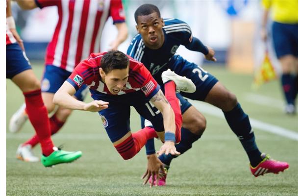 Vancouver WhitecapsÂ’ Carlyle Mitchell, right, trips Chivas USAÂ’s Eric Avila on a play that led to a yellow card for the CapsÂ’ centre-back.