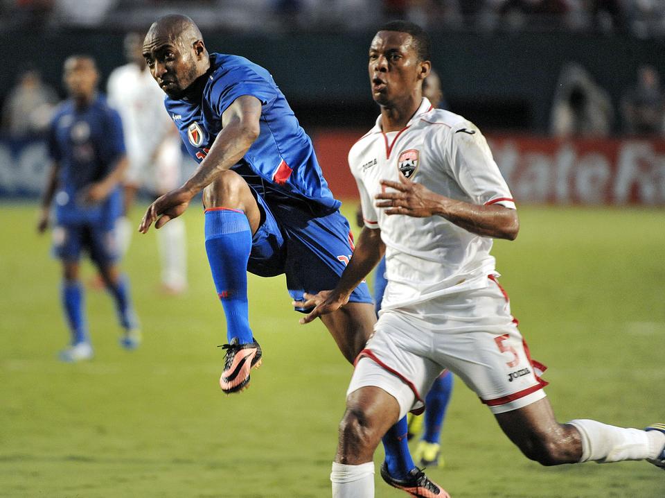 Haiti's Yves Hadley Desmaret takes a shot in front of Trinidad and Tobago's Carlyle Mitchell during the second half of their game, Friday, July 12, 2013, at Sun Life Stadium.