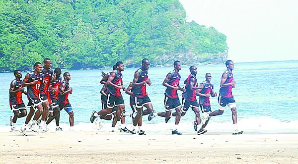 Joe Public captain, Carlyle Mitchell, right leads members of the Soca Warriors training squad Glenroy Samuel, Micah Lewis, Atuallah Guerra, Noel Williams, Andrei Pacheco, Marvin Phillip, Clyde Leon, Keston Williams, Akim Armstrong and Hughtun Hector jog under the supervision of national coach, Germany’s Otto Pfister on Las Cuevas Beach, yesterday. ...PHOTO: courtesy TTFF Media.