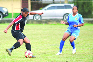 on the go: Trincity Nationals goalscorer Jonelle Warwick, left, fires a shot in a Trinidad and Tobago Women's League Football Premier League match against Defence Force at St George's College ground, Barataria. Trincity won 2-0. —Photo: Anisto Alves 