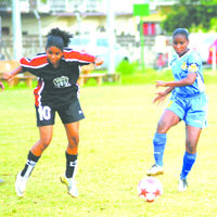 WOLF ACTION: Trincity Nationals player Elisa Olivero, left, and Simeone Connell of Defence Force contest the ball during a Trinidad and Tobago Women's League Football (WOLF) Premier League match at St George's College ground, Barataria last week Friday. Trincity Nationals won 2-0. –Photo: Anisto Alves