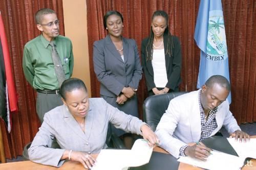 Dwight Yorke, seated right, signs on the dotted line, in the presence of administrator of the Division of Tourism Claire Davidson-Williams, seated left, Secretary of the Division of Tourism Tracy Davidson-Celestine, standing centre, Marketing Officer in the Division, Nigel Wilson, standing left, and Communications Specialist Aisha Sylvester.